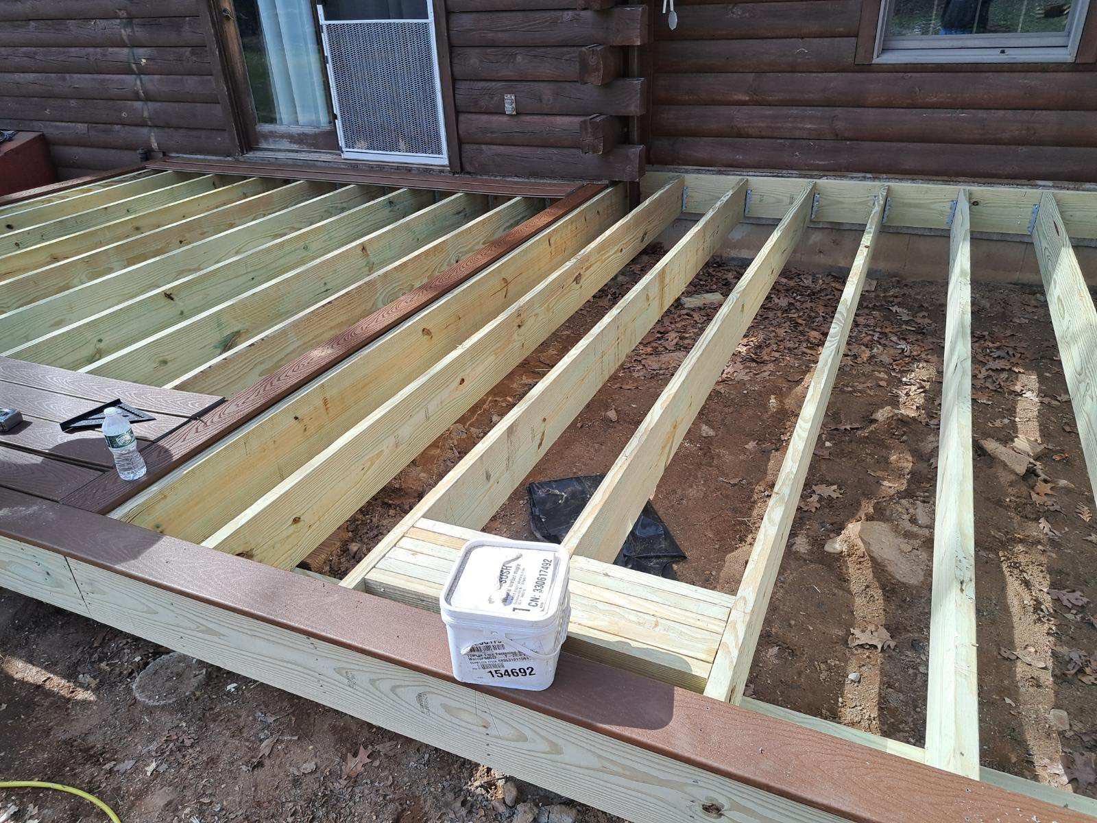 Deck Construction Lagace In-progress deck construction showing pressure-treated wood framing and composite decking installation at a log cabin home in Andover, CT project by Lagace Construction.