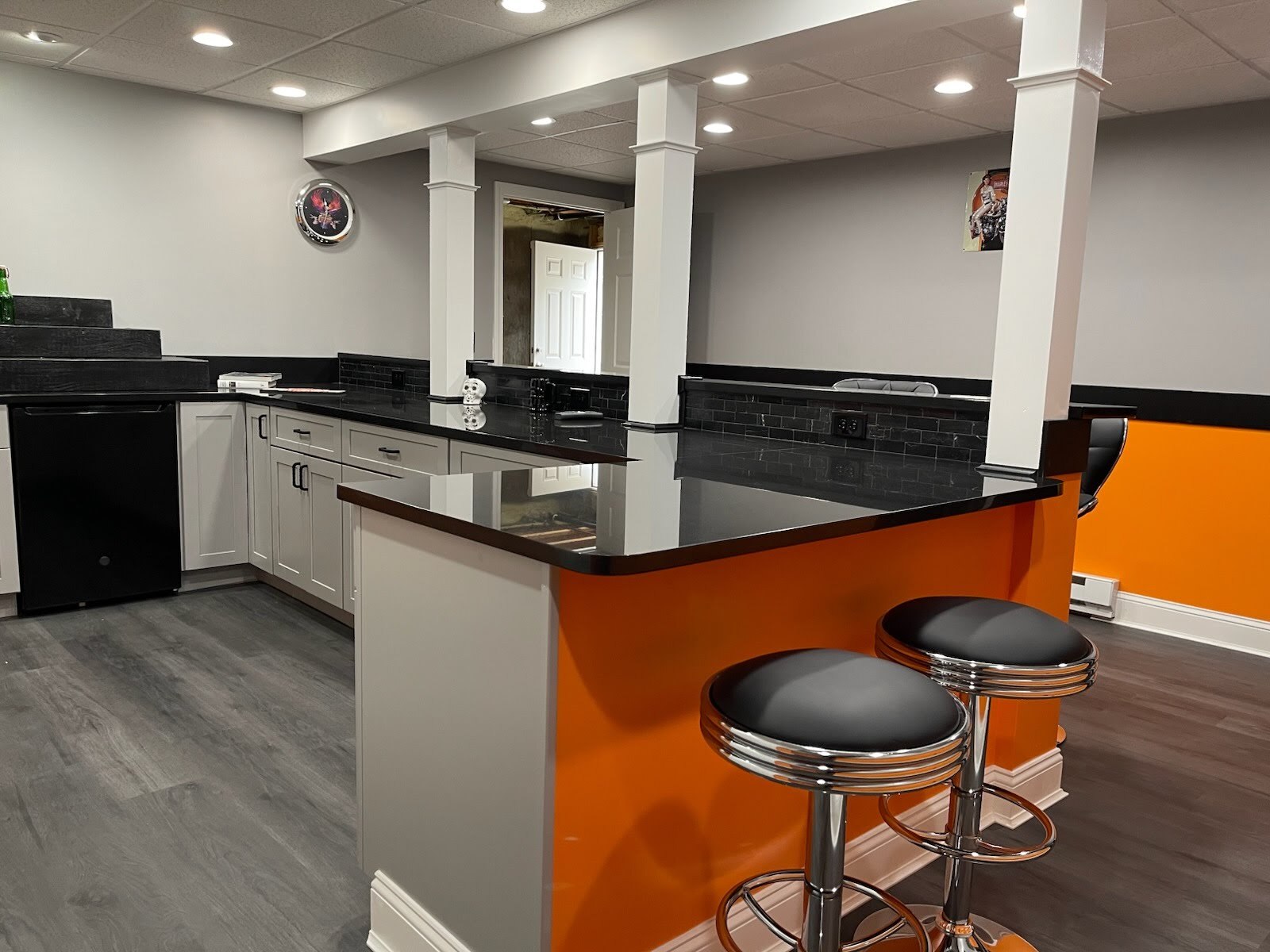 Kitchen in new home addition in Tolland CT Modern kitchen area in a newly built in-law suite addition in Tolland, Connecticut, featuring black countertops, white cabinets, and orange accent walls.